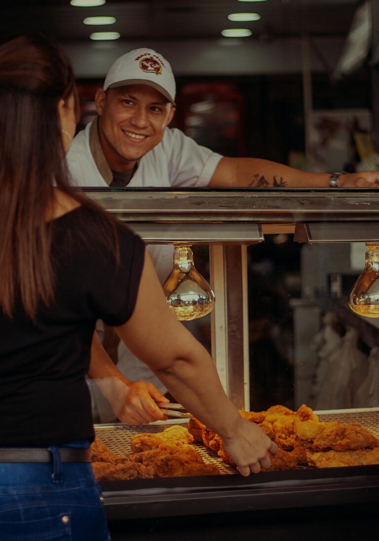 Chef interacting with customer while serving fried chicken in a Medellín restaurant setting.
